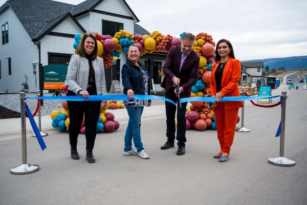 4 people standing in front of a balloon arch at a ribbon cutting ceremony